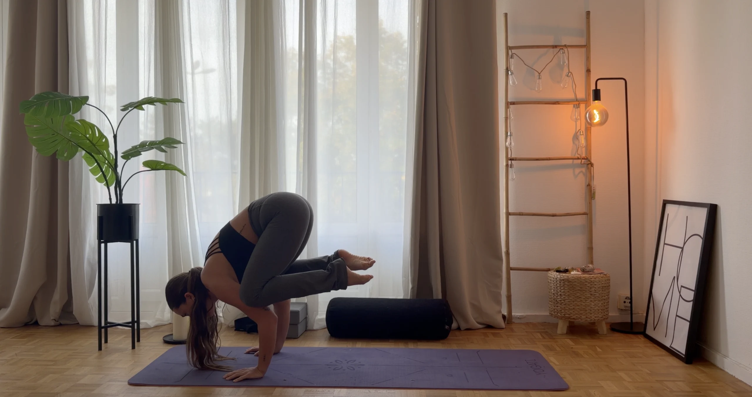 posture du corbeau, jambes pliées sur les bras