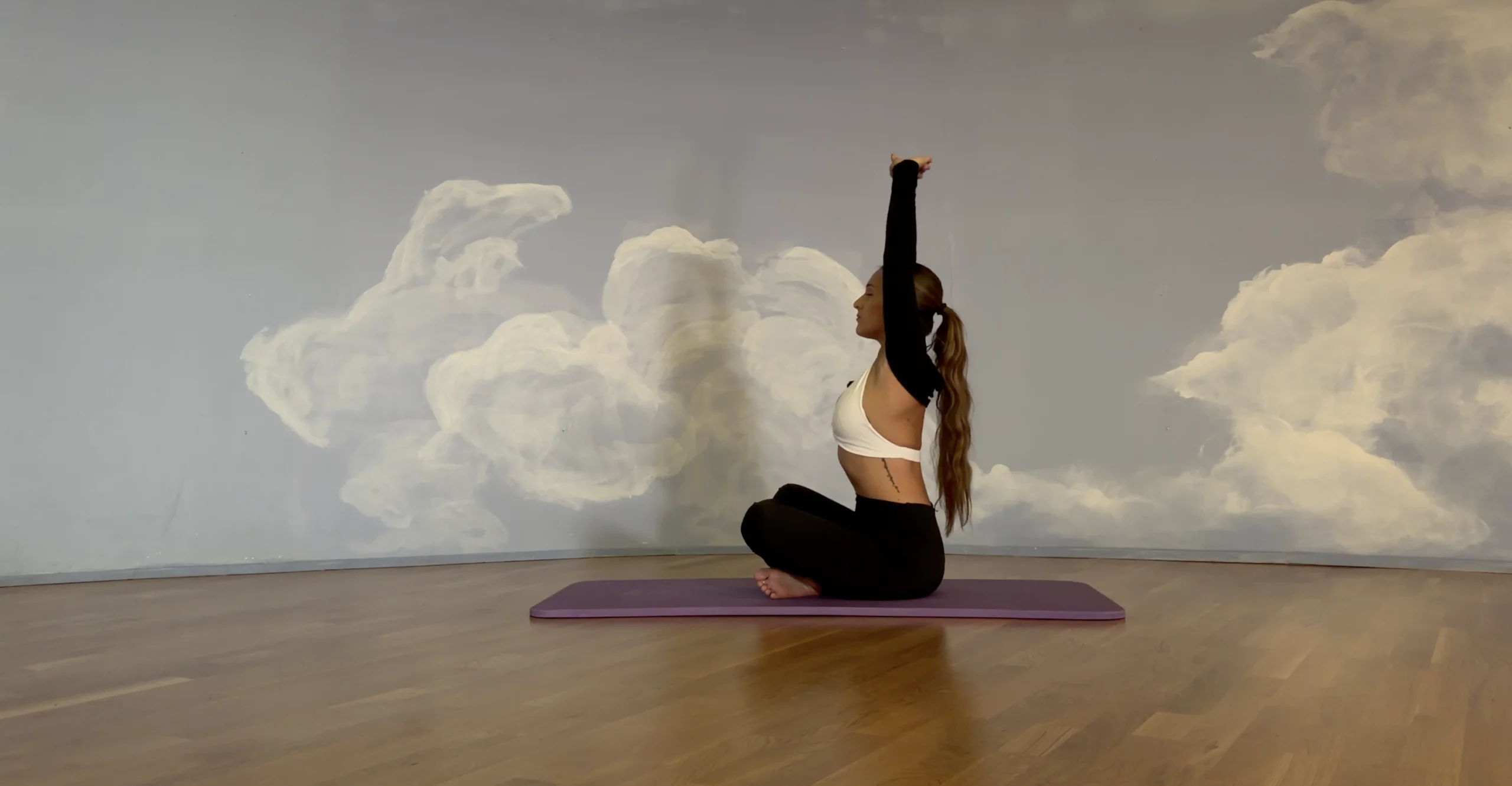 assise en tailleur les bras levés